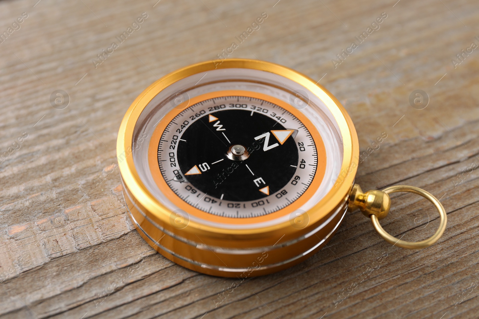 Photo of One compass on wooden table, closeup. Navigation equipment