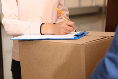Photo of Woman receiving parcel from delivery service courier indoors, closeup