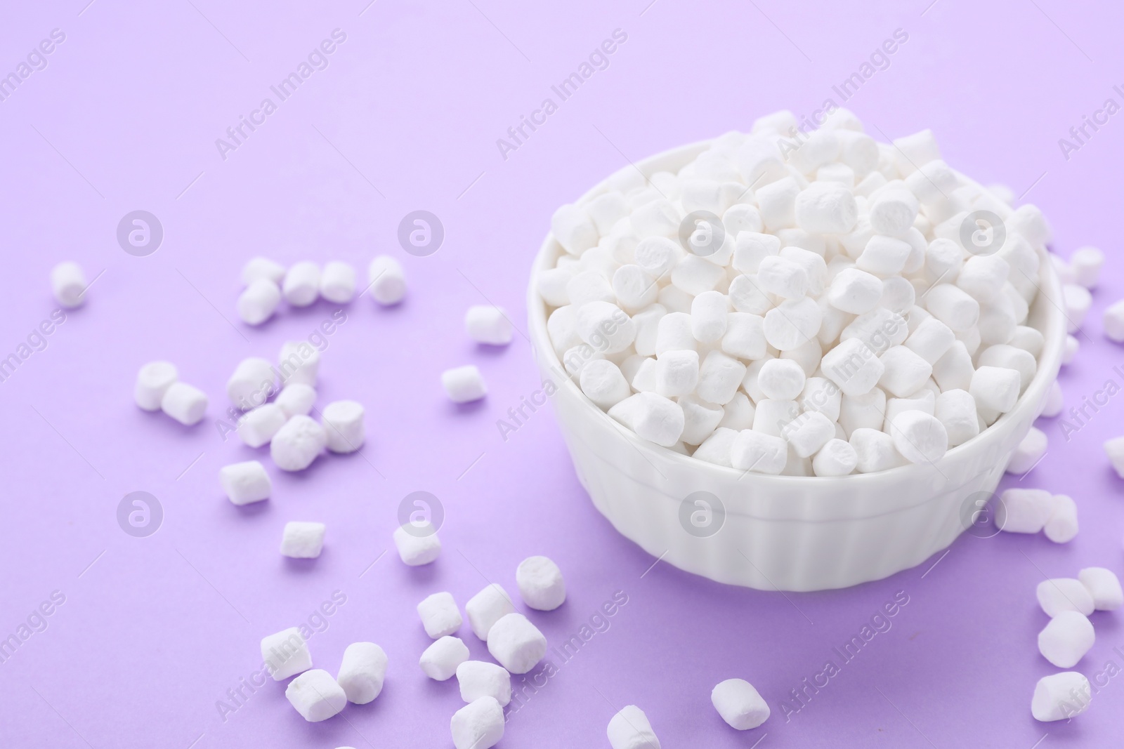 Photo of Bowl with delicious marshmallows on lilac background, closeup