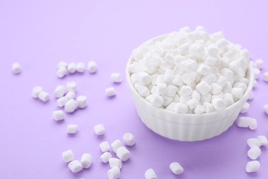 Photo of Bowl with delicious marshmallows on lilac background, closeup