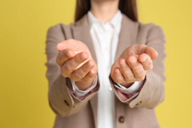 Photo of Young woman against yellow background, focus on hands