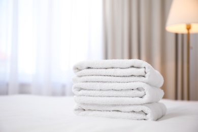 Photo of Stack of clean towels on bed indoors