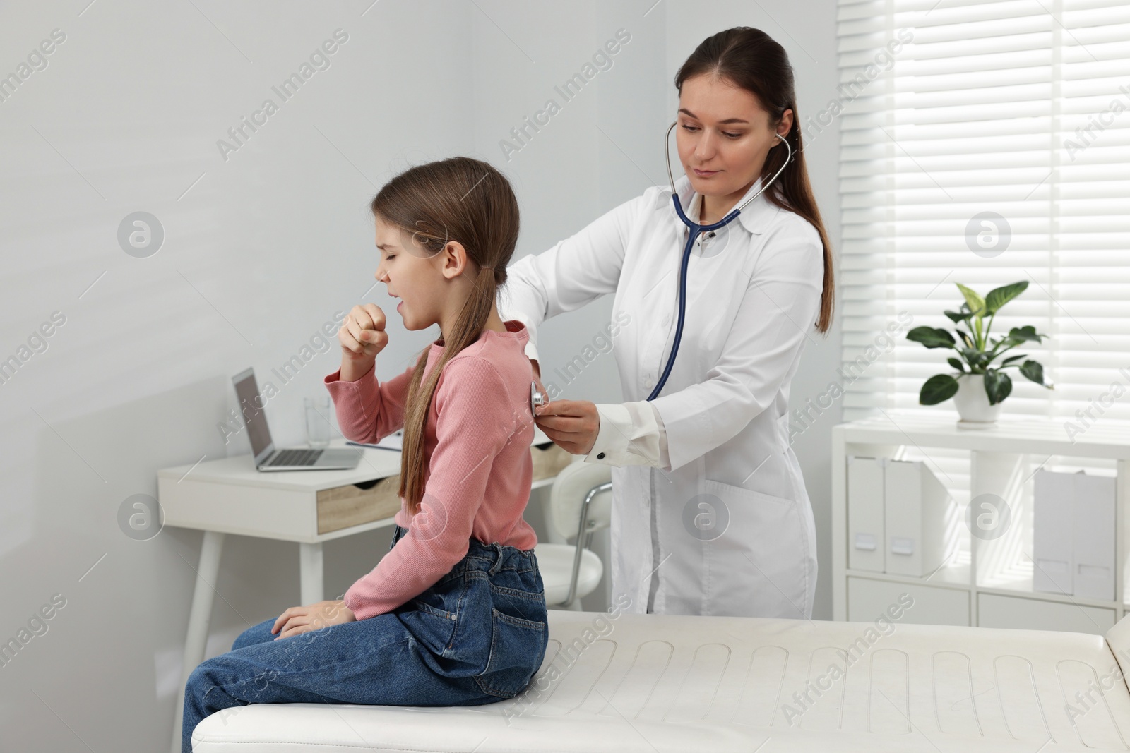 Photo of Doctor examining coughing girl in hospital. Cold symptoms