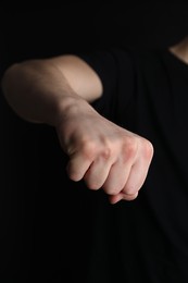 Photo of Man showing fist with space for tattoo on black background, closeup