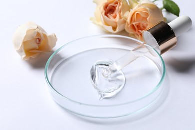 Petri dish with sample of cosmetic serum, pipette and rose flowers on white background, closeup