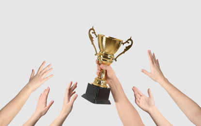 Image of People with golden trophy cup on light background, closeup