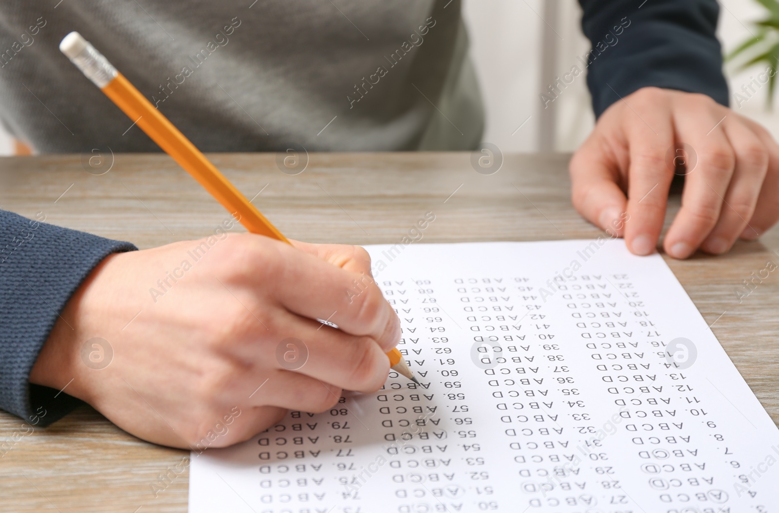 Photo of Student filling answer sheet at table, closeup