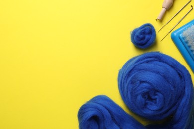 Blue wool and needle felting tools on yellow background, flat lay. Space for text