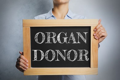 Image of Woman holding blackboard with text ORGAN DONOR on light background, closeup