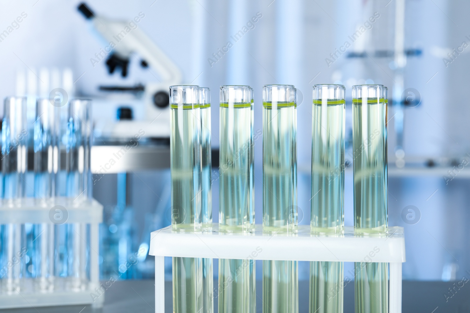 Photo of Test tubes with liquid on blurred background, closeup. Laboratory analysis