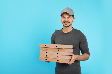 Young courier with pizza boxes on color background, space for text. Food delivery service