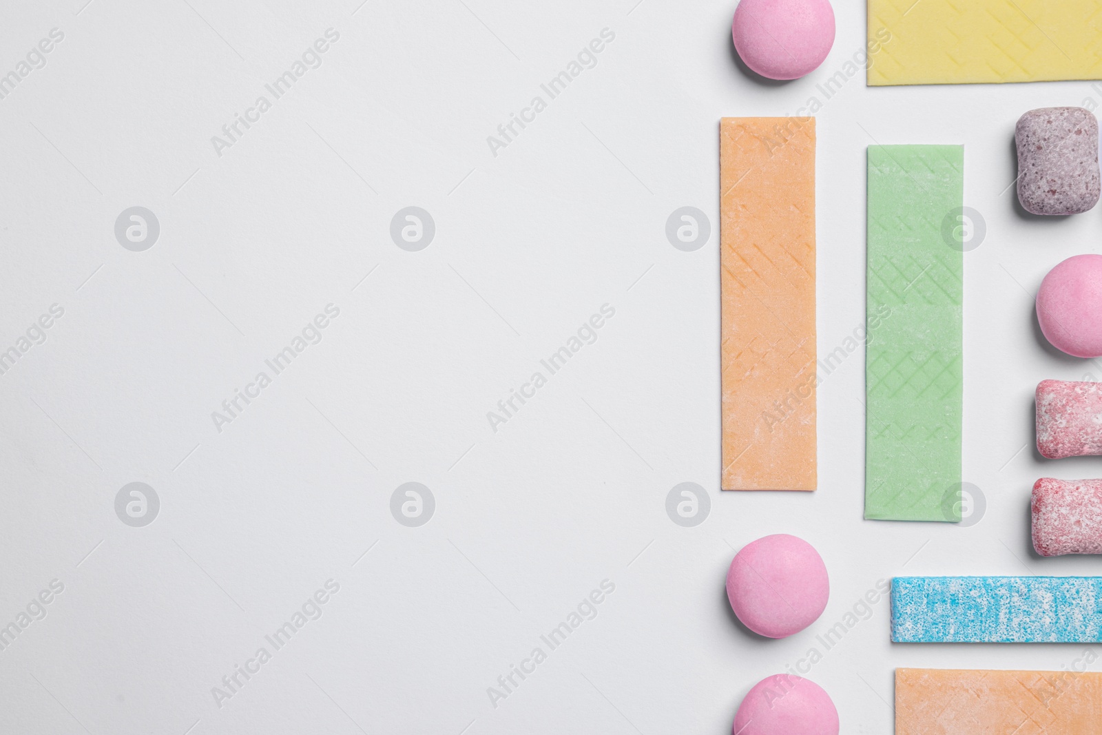 Photo of Different tasty colorful bubble gums on white background, flat lay. Space for text