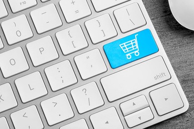 Image of Online store purchase. Light blue button with shopping cart on computer keyboard, top view