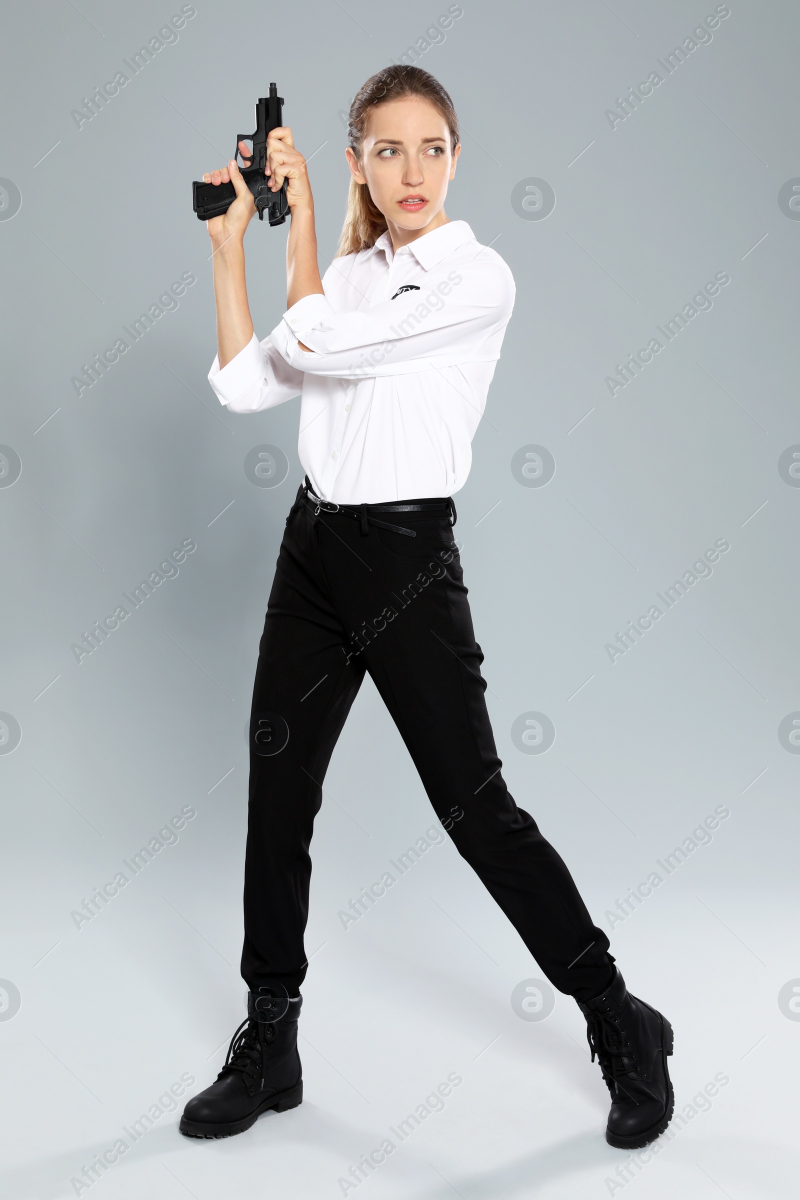 Photo of Female security guard in uniform with gun on grey background