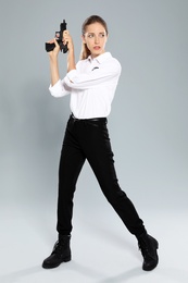 Female security guard in uniform with gun on grey background