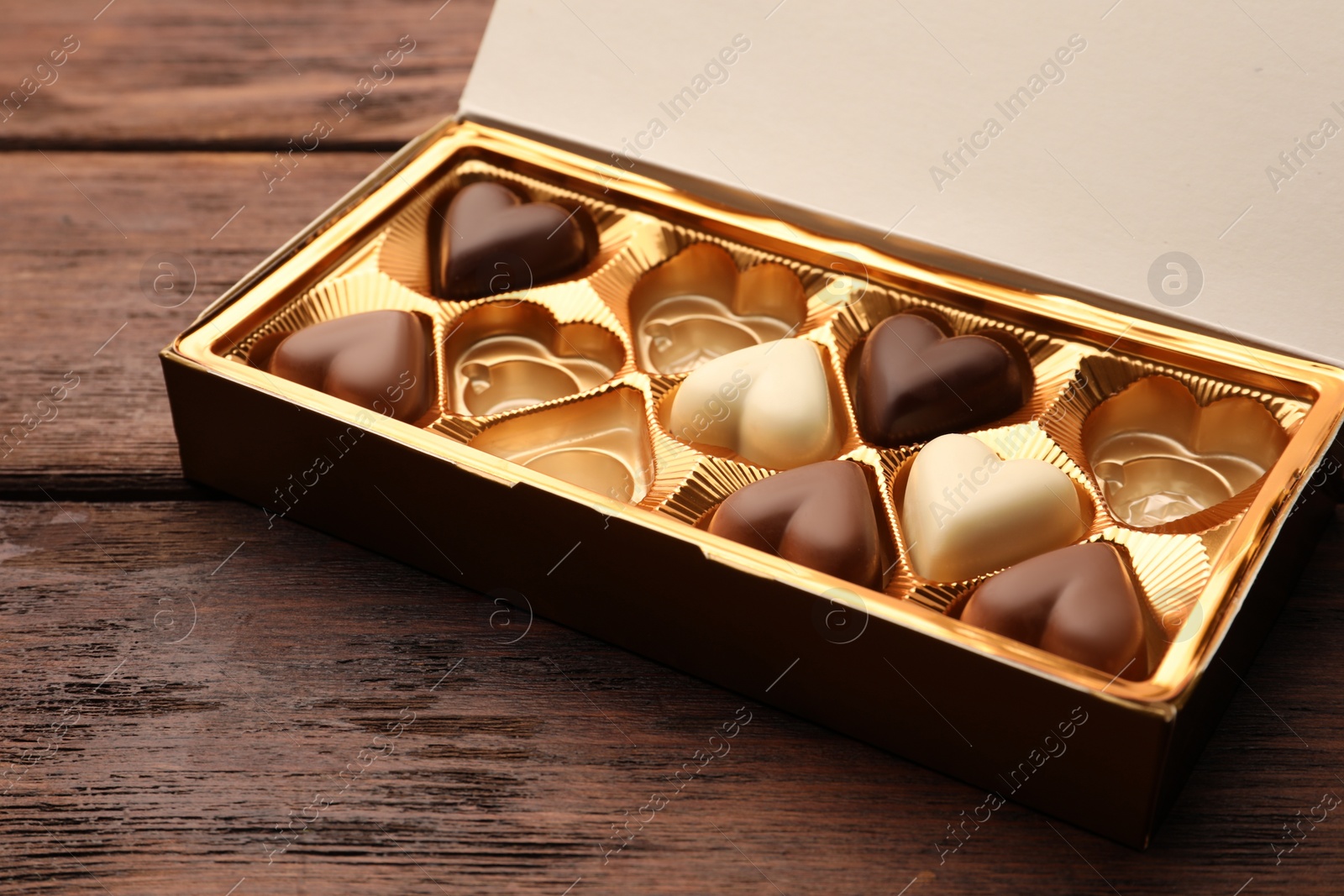 Photo of Partially empty box of chocolate candies on wooden table