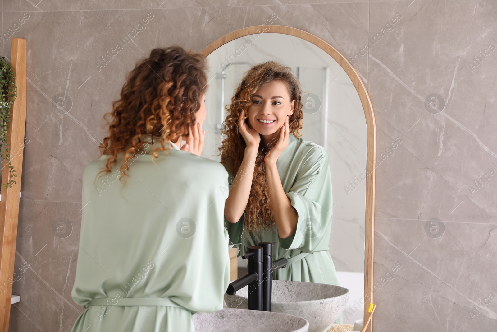 Photo of Beautiful woman looking at herself in bathroom mirror