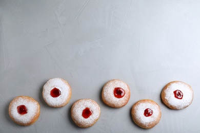 Hanukkah doughnuts with jelly and sugar powder on grey background, flat lay. Space for text
