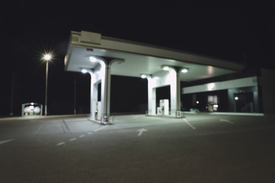 Photo of Blurred view of modern gas station with convenience store beside the road at night