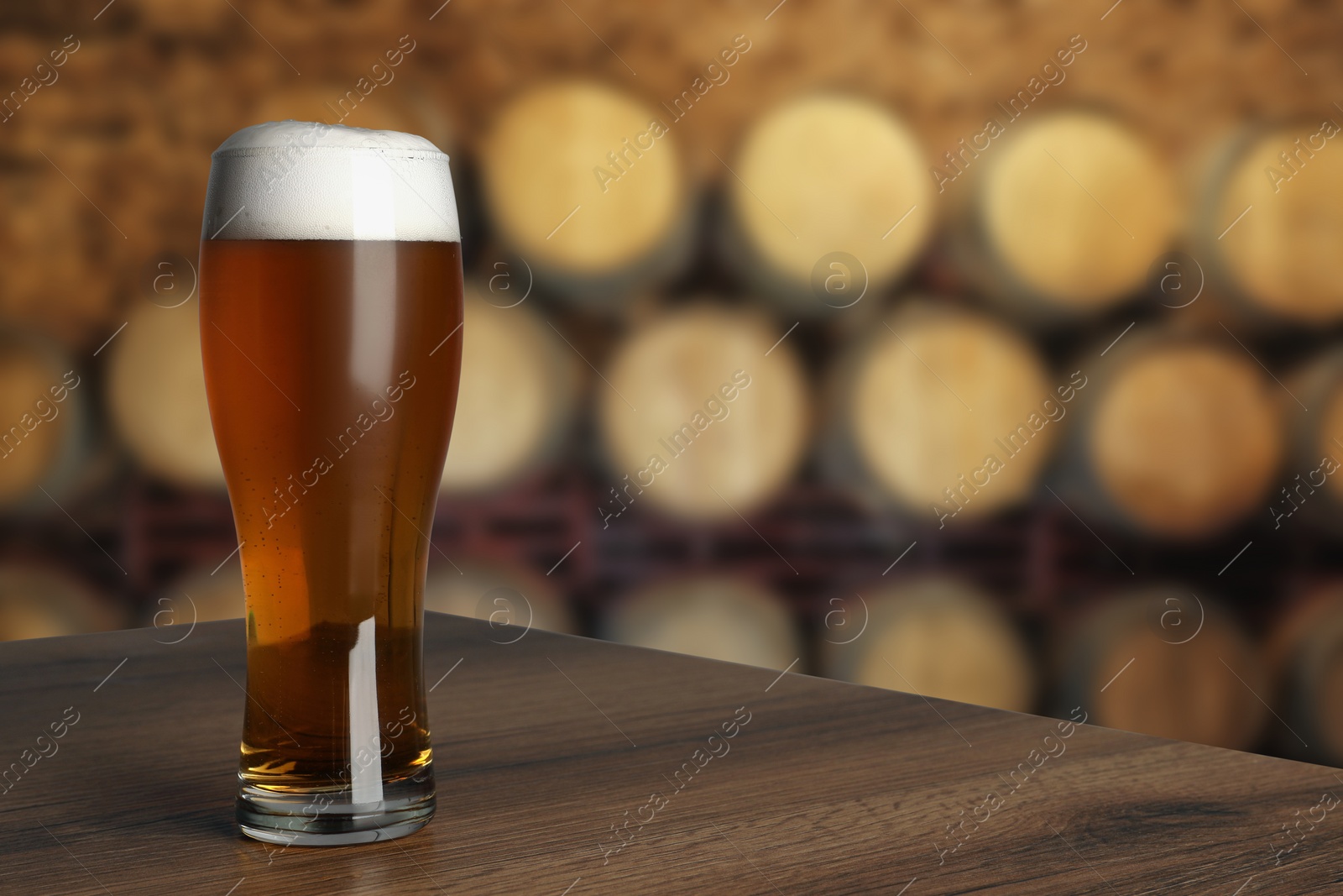 Image of Glass with fresh beer on wooden table in cellar, space for text