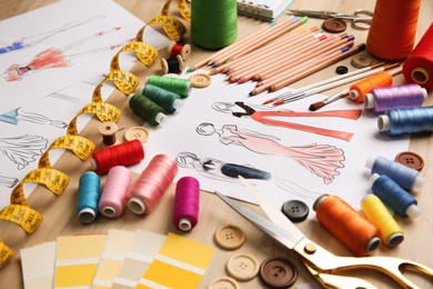 Photo of Sketches of fashion clothes and thread supplies at designer's workplace