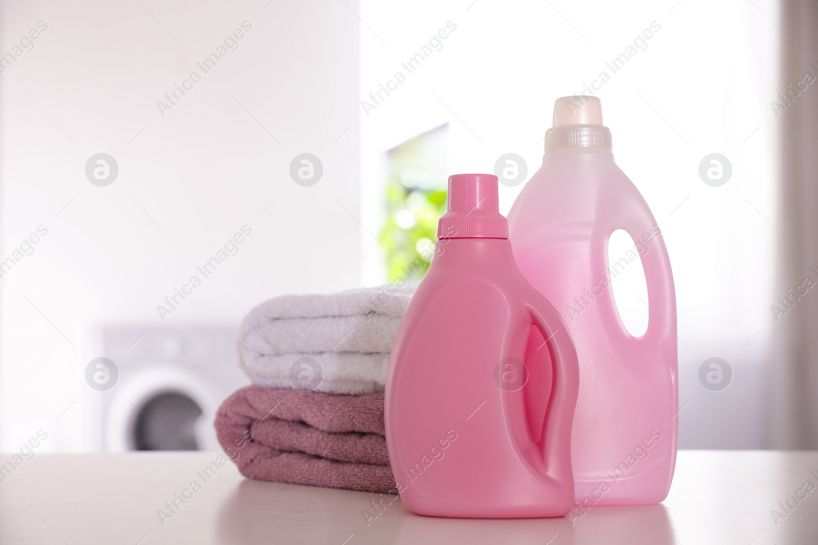 Photo of Stack of clean towels and detergents on white table indoors