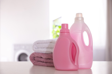 Photo of Stack of clean towels and detergents on white table indoors