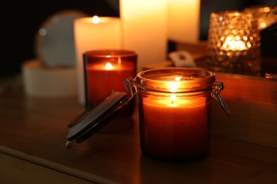 Lit candles on wooden table in dark room