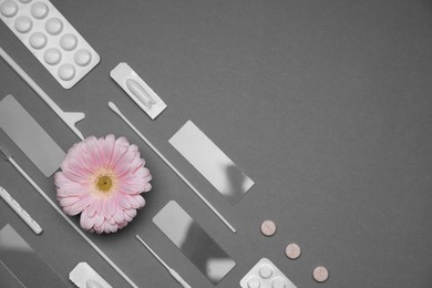 Photo of Many gynecological tools, pills and gerbera flower on grey background, flat lay. Space for text