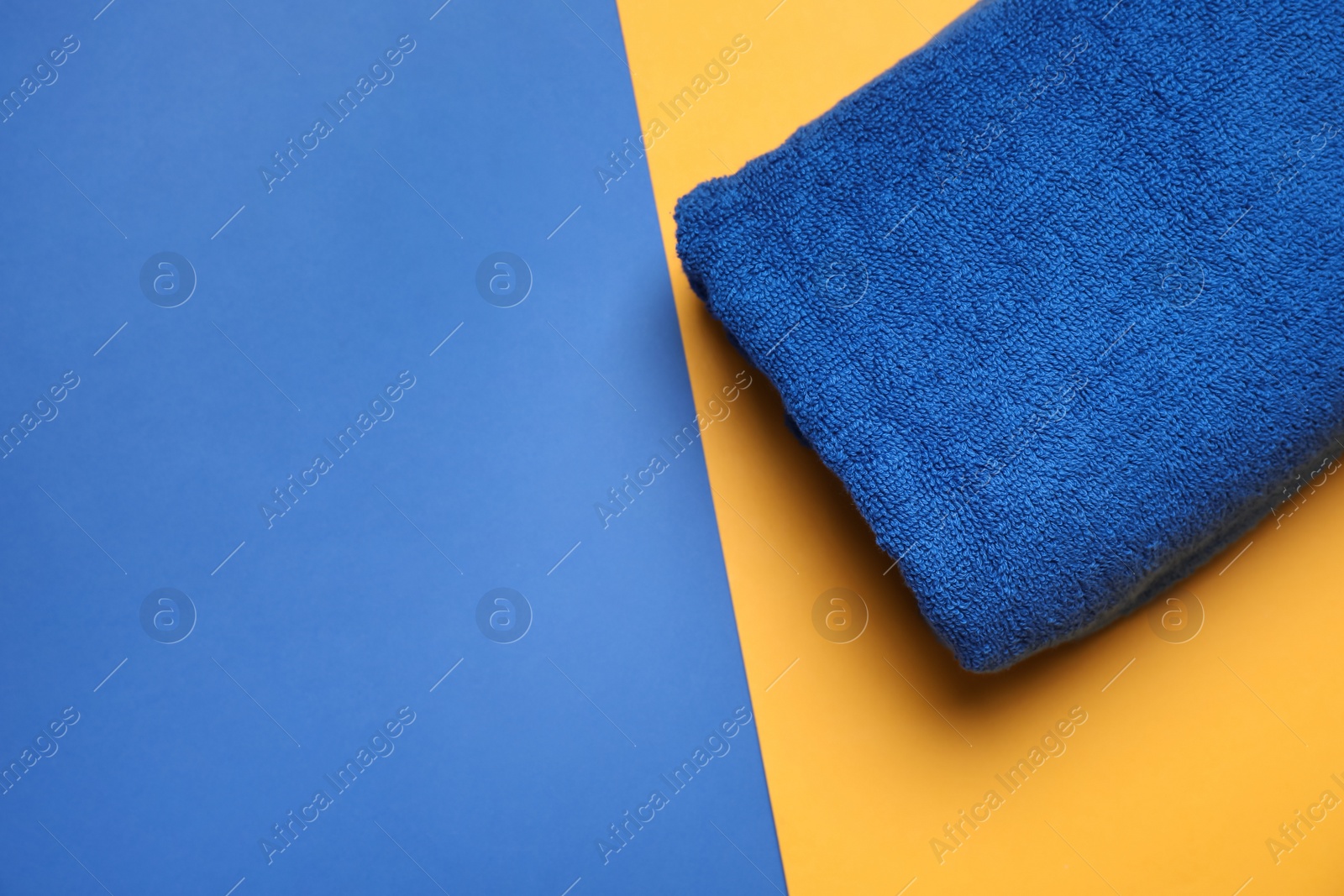 Photo of Soft folded towel on color background, top view. Space for text