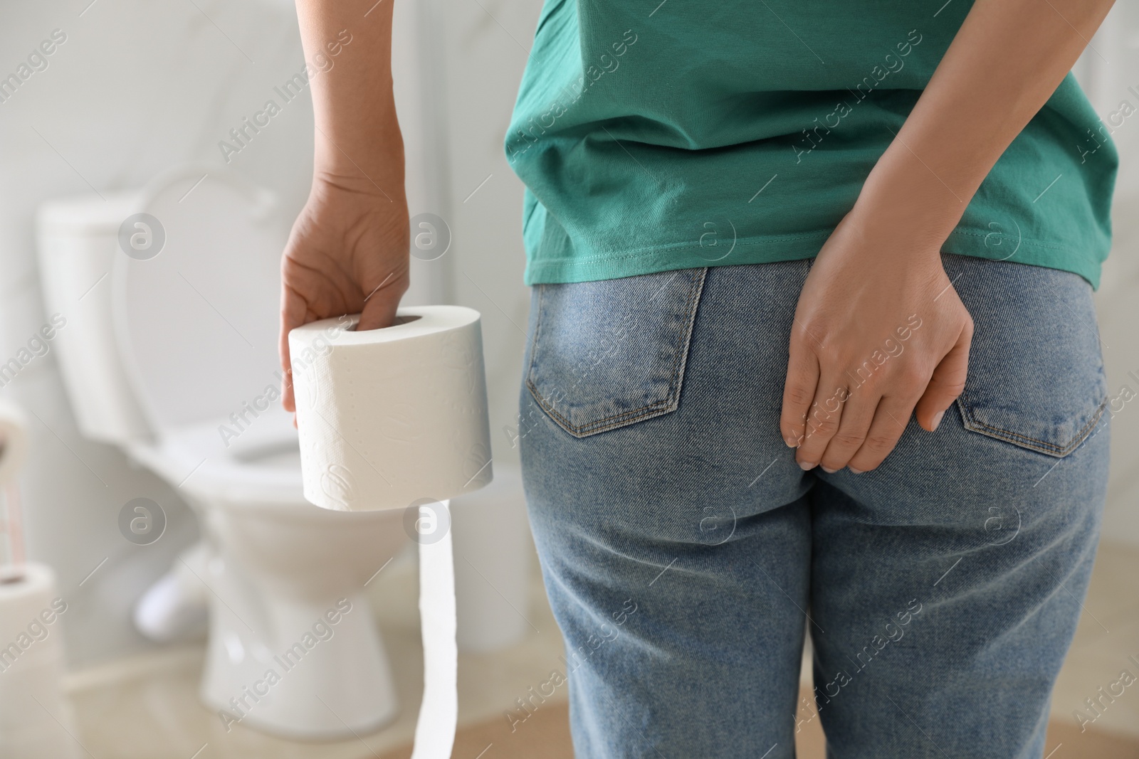 Photo of Woman with toilet paper suffering from hemorrhoid in rest room, closeup