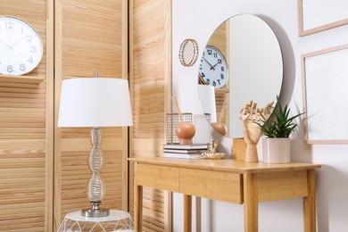 Photo of Modern wooden dressing table with mirror and decorative elements indoors