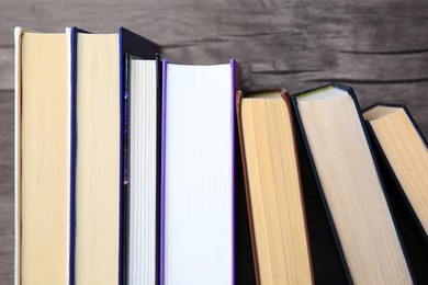 Collection of different books near wooden wall, closeup