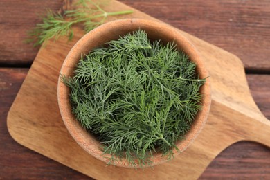 Photo of Bowl of fresh dill on wooden table, top view