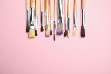 Photo of Different paint brushes on color background, top view with space for text