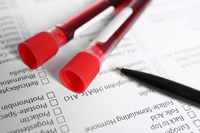 Photo of Test tubes with blood samples for analysis on laboratory test form, closeup