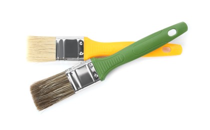 Photo of Two paint brushes with colorful handles isolated on white, top view