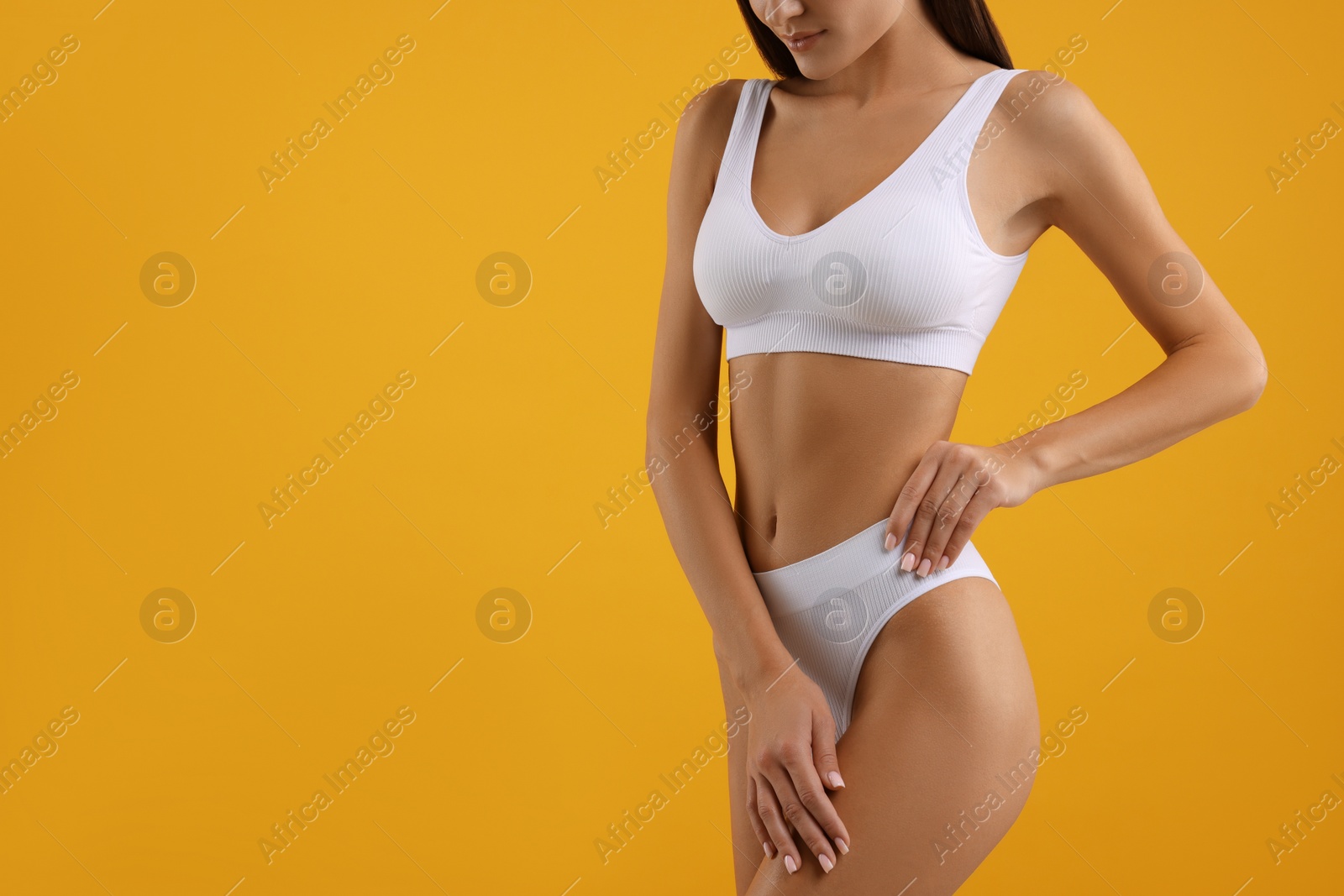 Photo of Young woman in stylish white bikini on orange background, closeup. Space for text