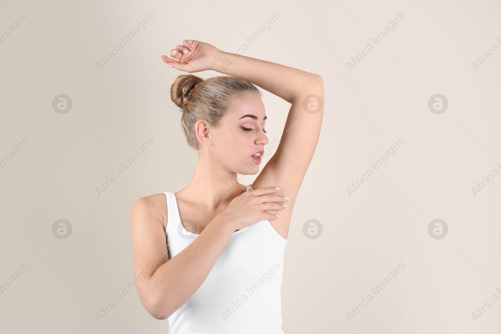 Photo of Young woman showing armpit on color background. Using deodorant