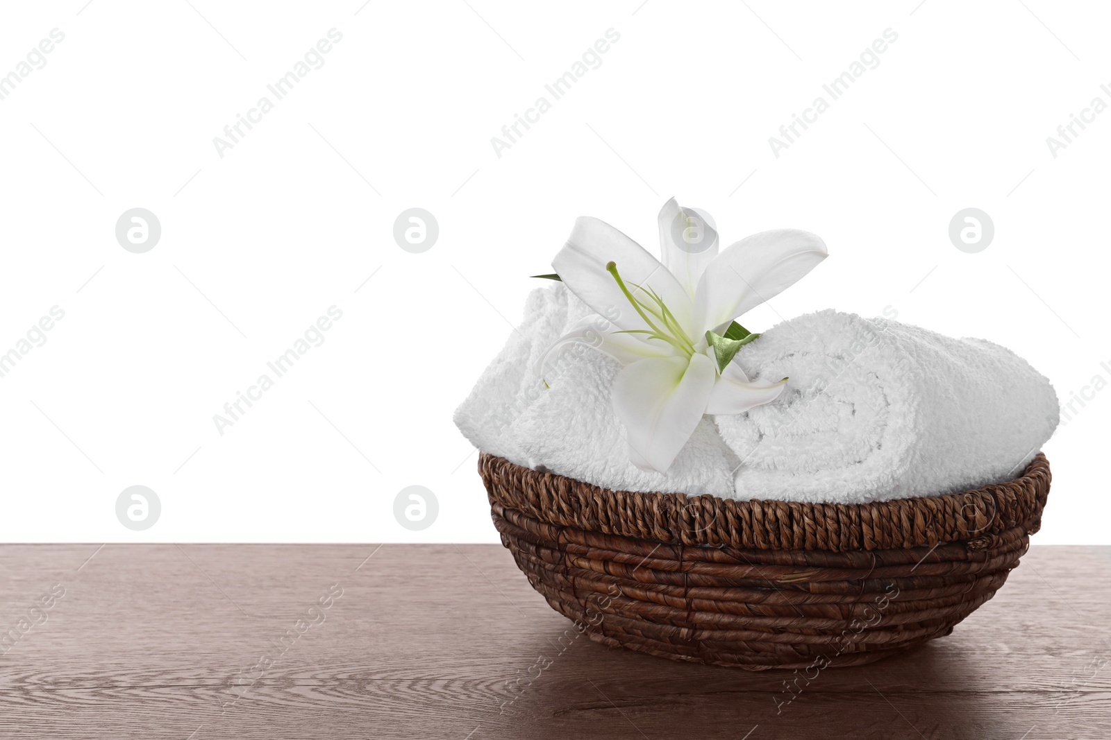 Photo of Fresh towels and lily flower on wooden table against white background. Space for text