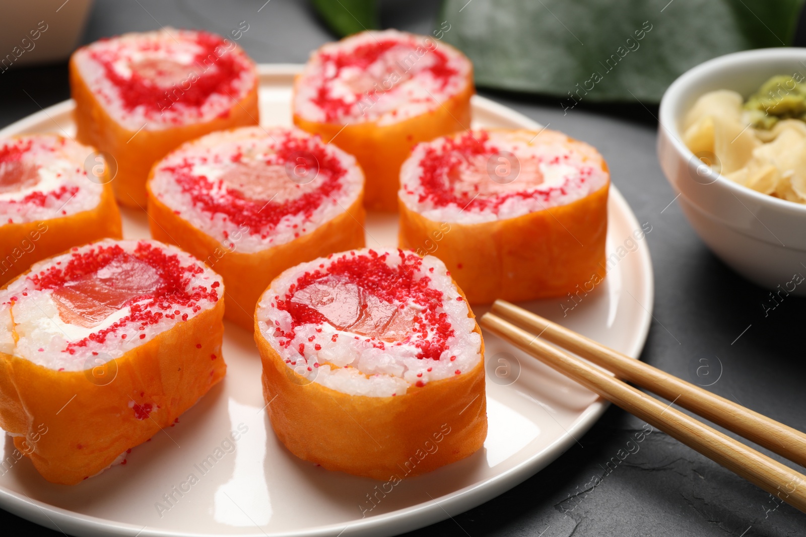 Photo of Delicious sushi rolls with salmon and tobiko on grey textured table, closeup