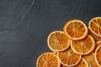 Photo of Many dry orange slices on black textured table, flat lay. Space for text