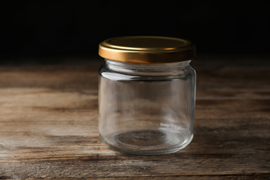 Photo of Closed empty glass jar on wooden table