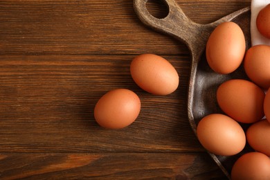 Photo of Raw brown chicken eggs on wooden table, flat lay. Space for text