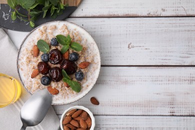 Photo of Tasty wheat porridge with milk, dates, blueberries and almonds in bowl served on light wooden table, flat lay. Space for text