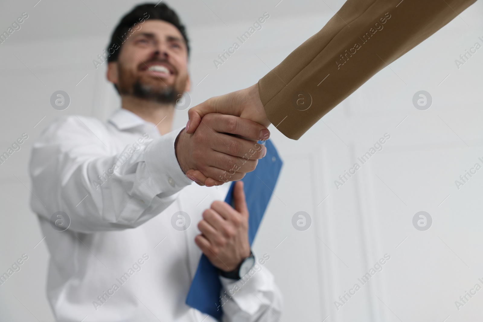 Photo of Human resources manager shaking hands with applicant during job interview in office, selective focus