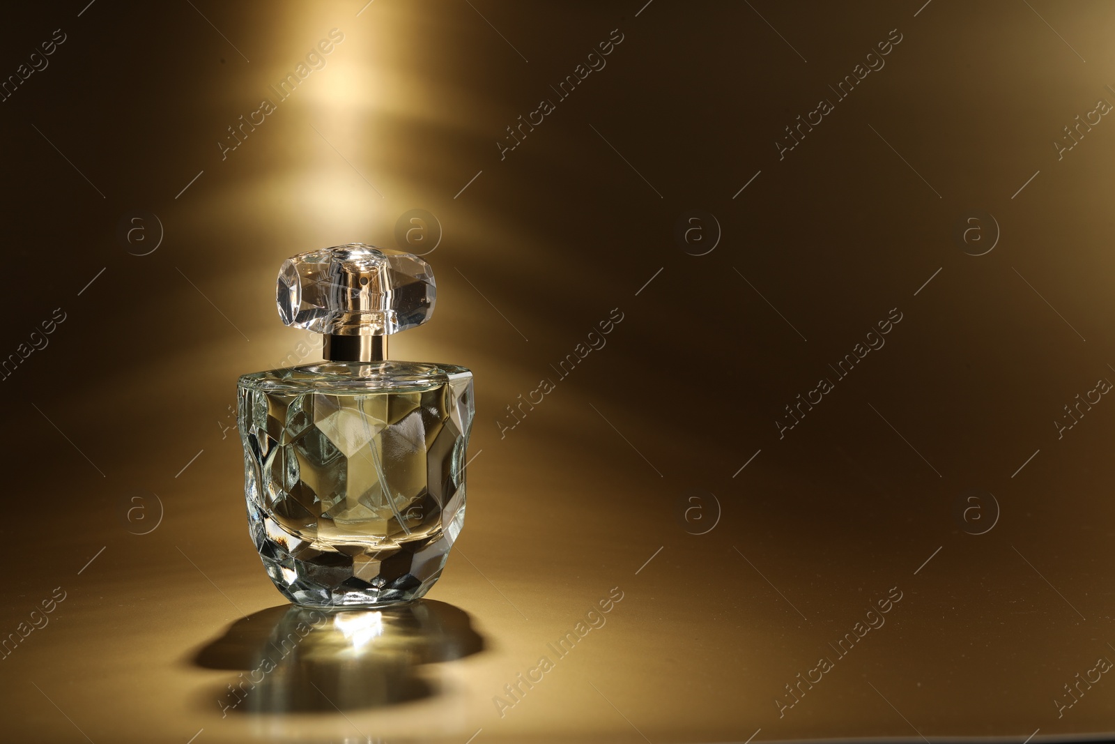 Photo of Luxury women's perfume. Sunlit glass bottle on golden background, space for text