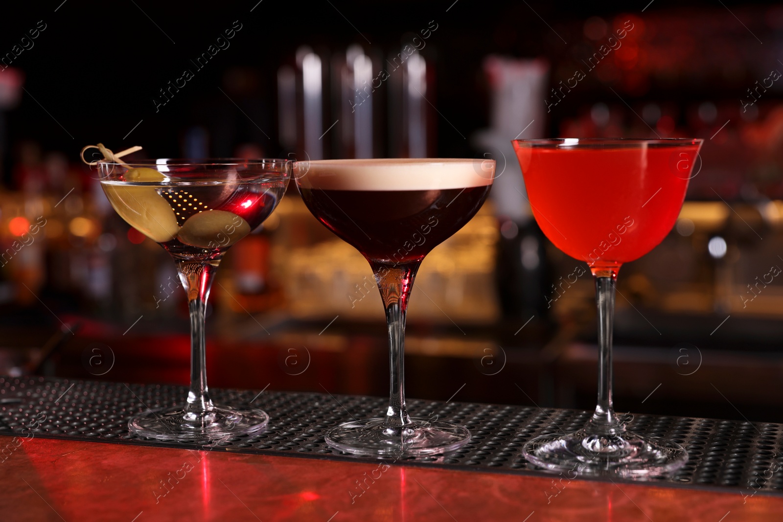 Photo of Glasses of different Martini cocktails on bar counter