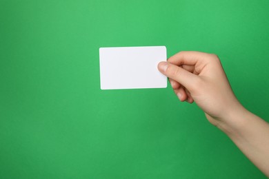 Photo of Woman holding blank gift card on green background, closeup