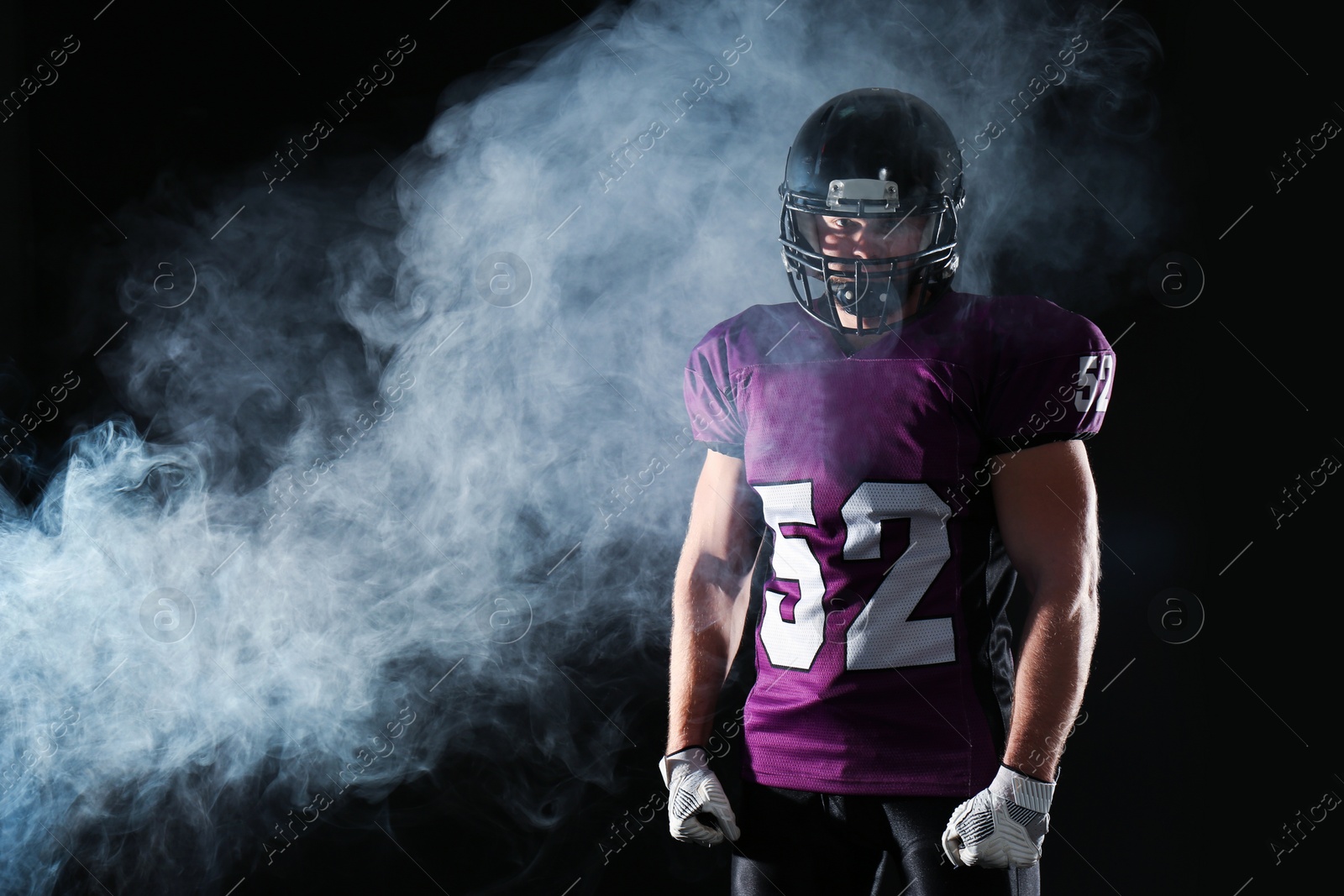 Photo of American football player wearing uniform on dark background. Space for text